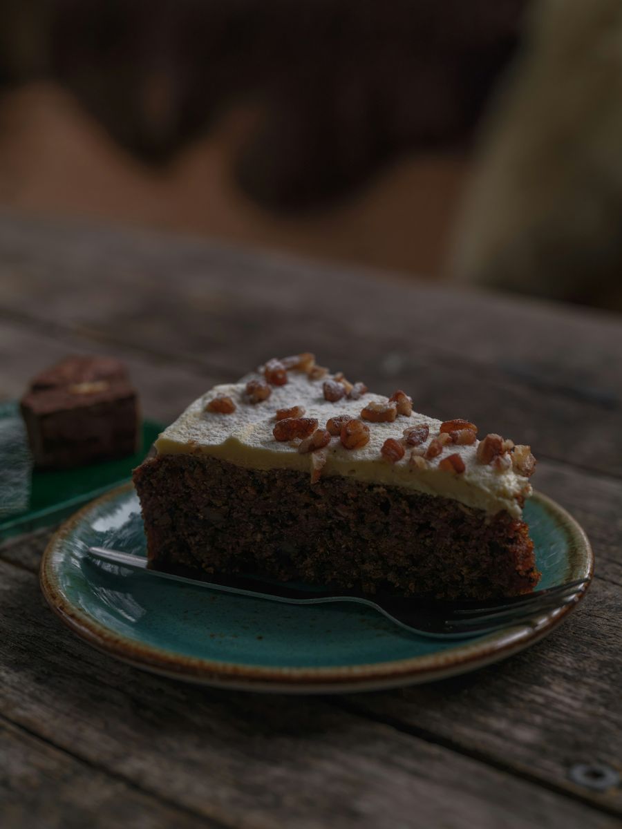 A slice of carrot cake with cream cheese icing on a green plate